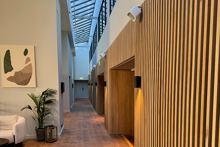 Hotellkorridor med panelvägg av trä samt högtalare